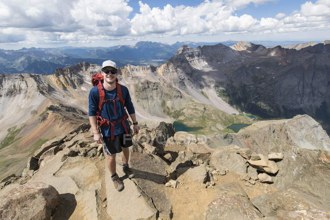 Улыбающийся мужчина-турист стоит на скалистой горе — стоковое фото