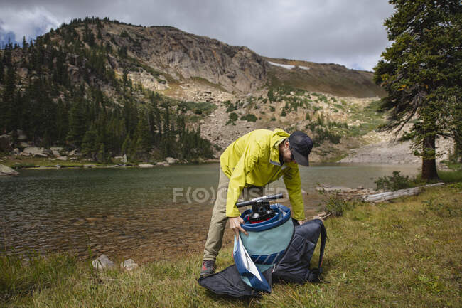 Mann packt Paddelbrett aus Rucksack am Seeufer — Stockfoto