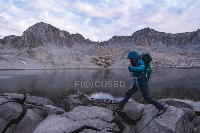 Seitenansicht einer Frau, die am See auf Felsen spaziert — Stockfoto