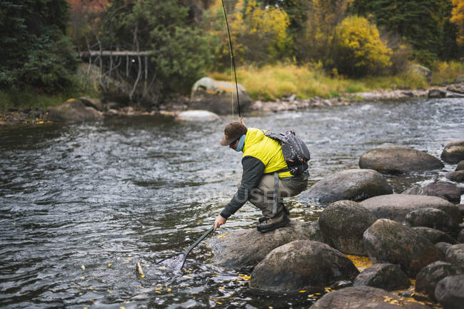 Vista lateral do homem pesca com mosca no rio Roaring Fork durante o outono — Fotografia de Stock