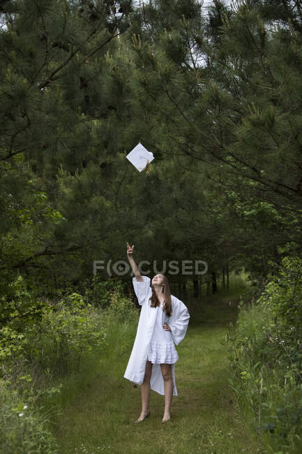 Happy Feminino Graduado vestindo branco Tosses Graduação Cap — Fotografia de Stock