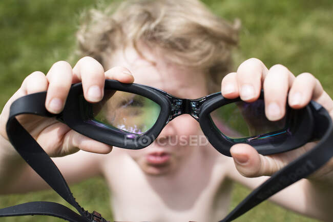 Fuera de foco pequeño chico mira a través de en foco par de gafas - foto de stock