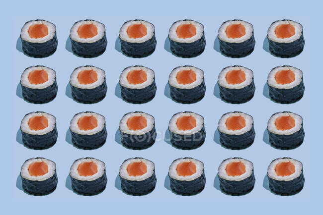 Rollo de sushi con salmón, aguacate, queso crema y salsa de tomate sobre un fondo blanco. - foto de stock