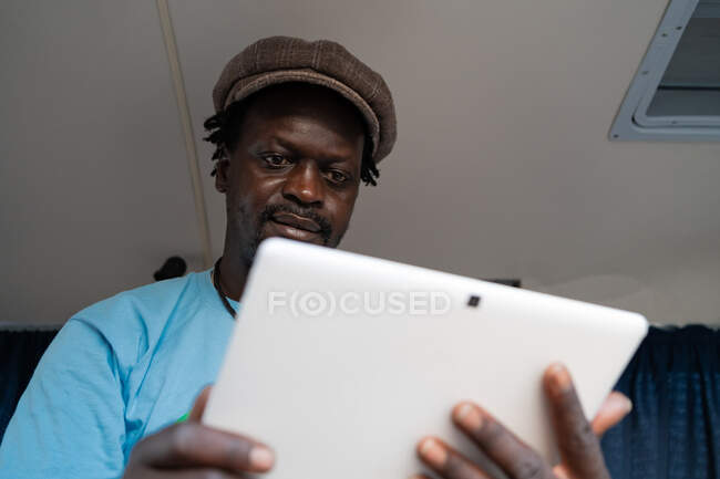 Africano nero ragazzo lavoro con tablet all'interno un van — Foto stock