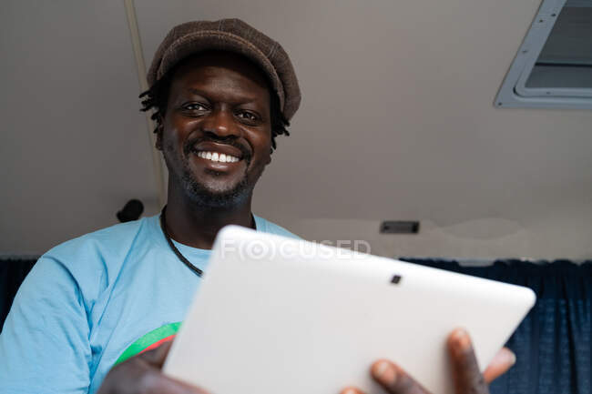 Afrikanischer schwarzer Junge arbeitet mit Tablet im Lieferwagen — Stockfoto
