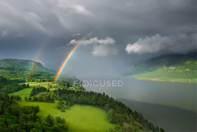 Schöne Landschaft mit Regenbogen und wolkenverhangenem Himmel — Stockfoto