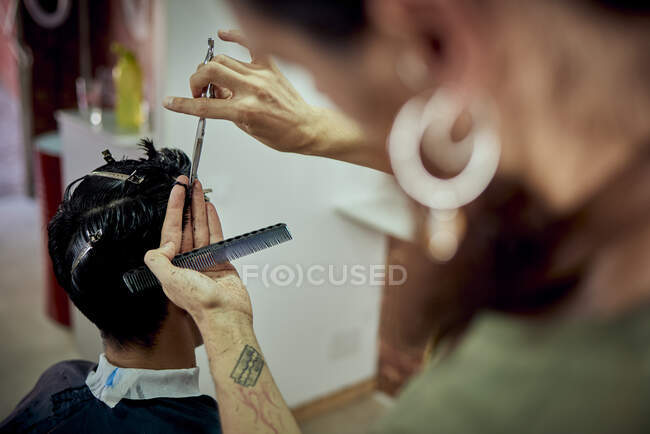 Мужчина стрижет волосы у коричневого мальчика. парикмахерская — стоковое фото