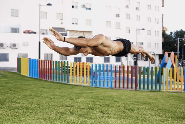 Un jeune homme qui fait des sauts calisthéniques dans un parc coloré. Concept calisthénique — Photo de stock