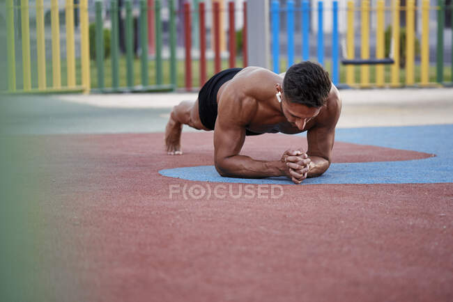 Ein junger Mann macht Calisthenics auf einem farbigen Fußboden. Calisthenisches Konzept — Stockfoto