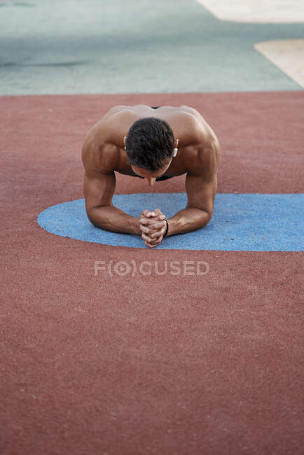 Un joven haciendo calistenia en un suelo de color. Concepto calisténico - foto de stock