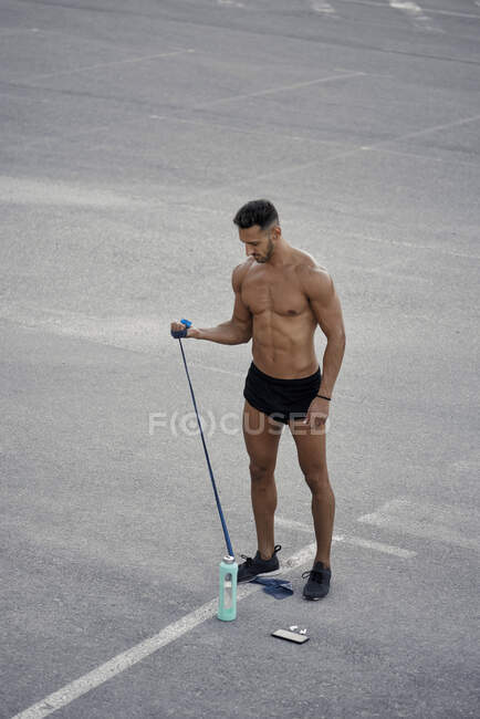 Ein athletischer Mann, der Calisthenics mit einem Gummiband macht. Calisthenisches Konzept — Stockfoto