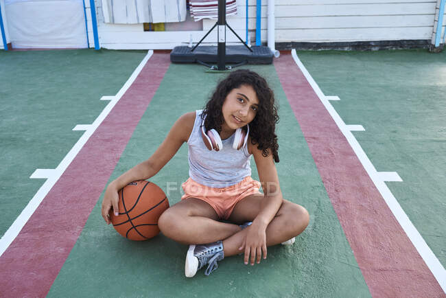 Дівчина, що сидить з баскетболом перед камерою, концепція стилю життя — стокове фото