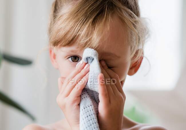 Close up portrait of a young girl holding her comforter closing an eye — Stock Photo