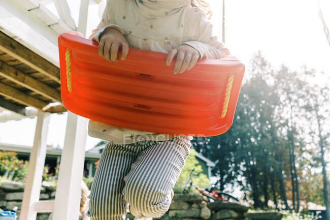Little toddler girl holding on to her swing while flying through air — Stock Photo