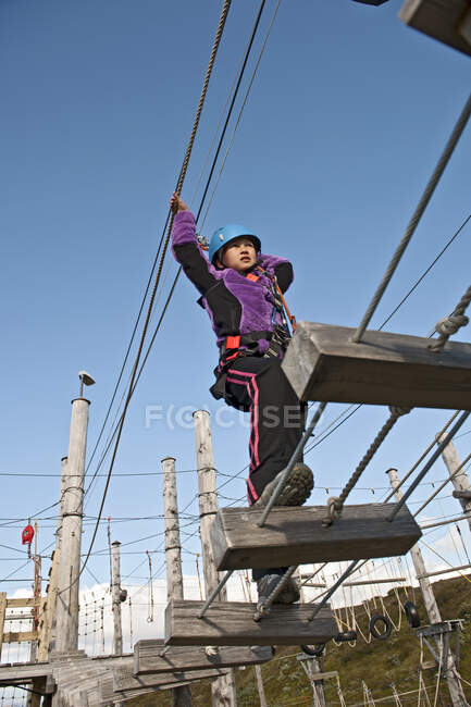Menina está equilibrando sobre uma ponte em curso de acesso de corda alta na Islândia — Fotografia de Stock