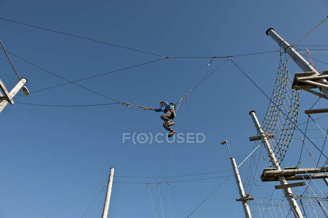 Menino em um balanço elevado em curso de acesso de corda alta na Islândia — Fotografia de Stock
