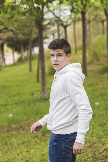 Side view young man standing outdoors while looking camera — Stock Photo