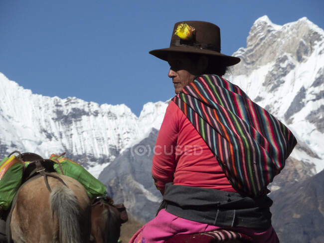 Eine Peruanerin mit Hut reitet auf einem Pferd im Hochgebirge — Stockfoto