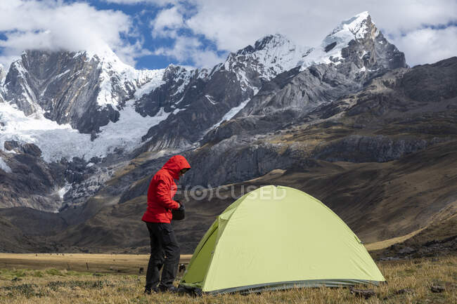 Una donna in piedi in un campo di alta quota vicino a una tenda a Huayhuash — Foto stock