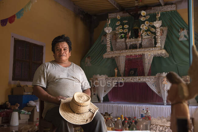 Un uomo seduto a casa sua mentre prepara un altare monumentale — Foto stock