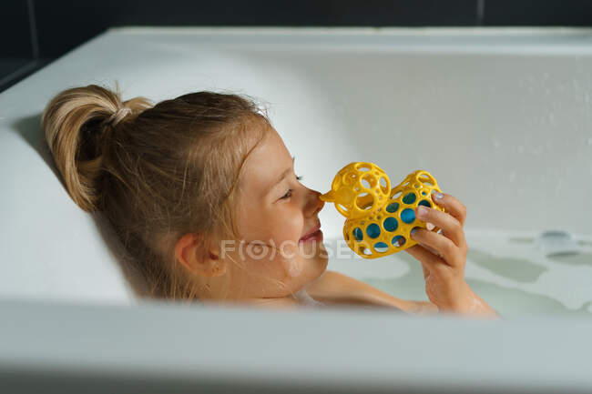 Portrait of a smiling young girl in bath with a rubber duck. — Stock Photo