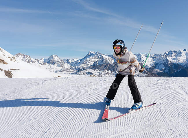 Un niño esquiando en la nieve blanca de Formigal con las montañas de los Pirineos en el fondo. Fotografía horizontal - foto de stock