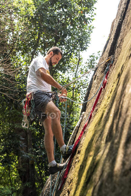 Vista para o homem escalada na parede rochosa na floresta tropical — Fotografia de Stock