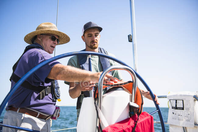 Homem aprendendo a navegar durante uma vela familiar no dia ensolarado de verão — Fotografia de Stock