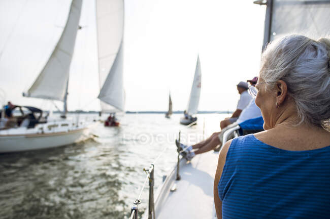 Mujer de mediana edad disfrutando de la carrera de vela de verano durante la hora dorada - foto de stock