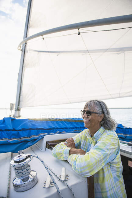 Жінка середнього віку насолоджується літнім вітрилом під час золотої години — стокове фото