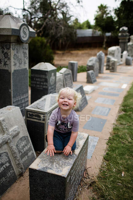 Двухлетний ребенок сидит на могиле и улыбается — стоковое фото