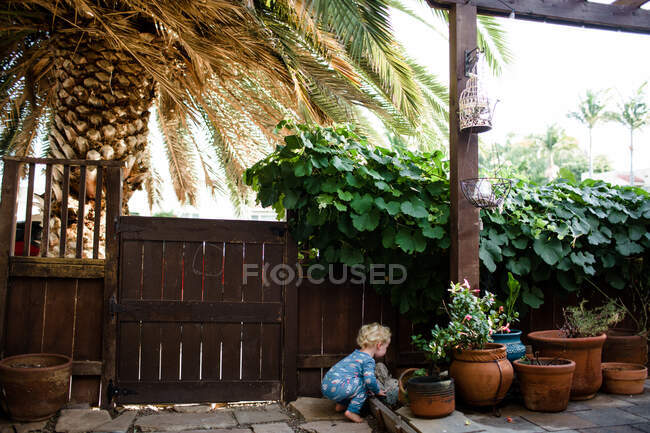 Niño de dos años agachado en el patio - foto de stock