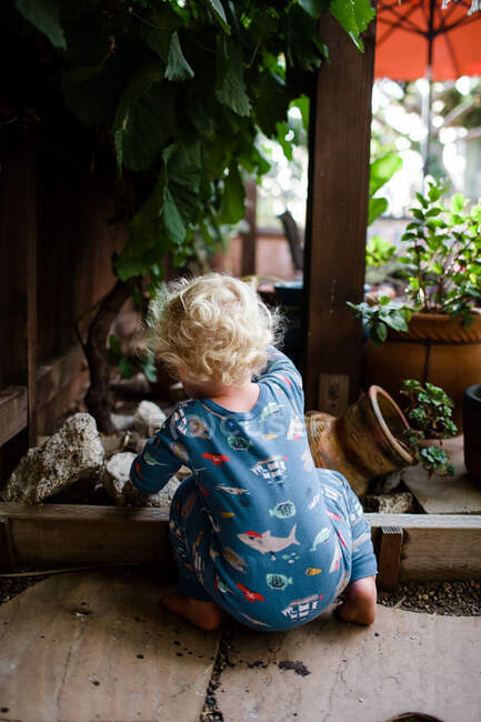 Blick von hinten auf einen zweijährigen Jungen, der unter Weinreben kauert — Stockfoto
