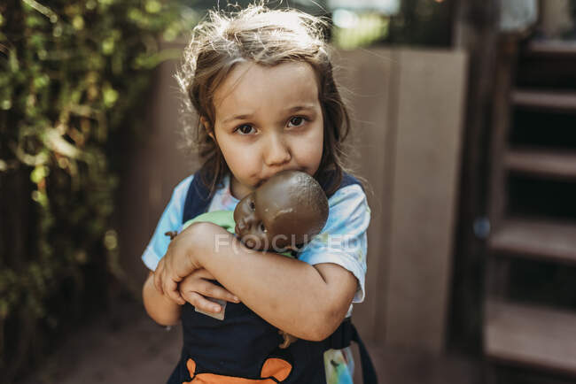 Close up of young girl cuddling with favorite baby doll outside — Stock Photo