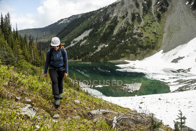 Backpacker walking near mountain lake — Stock Photo