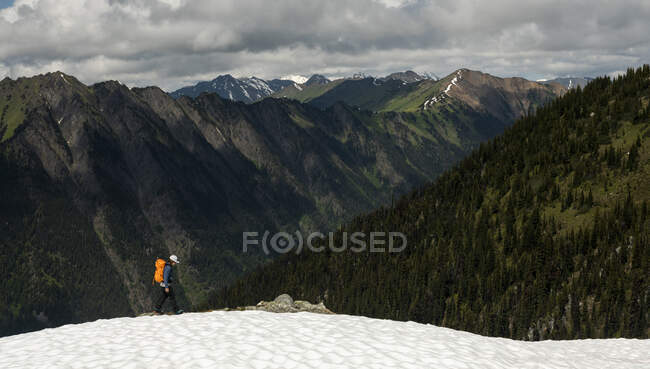 Hiker walking on snowy mountain slope — Stock Photo