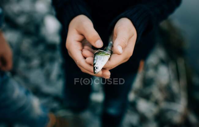 Young boy holding his first fish catch while fishing with family — стоковое фото