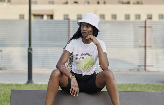 Bella donna nera che guarda di lato seduta in un parco — Foto stock