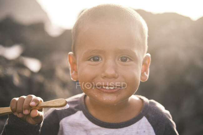 Niño pequeño cepillándose los dientes al aire libre - foto de stock