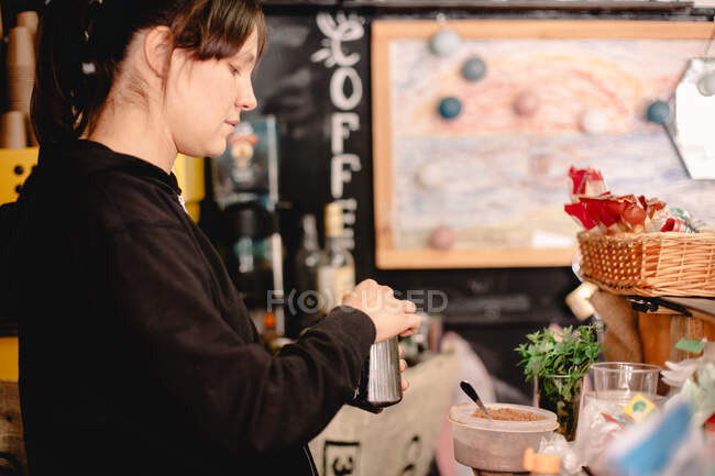 Женщина-бариста готовит кофе, стоя в кафе — стоковое фото