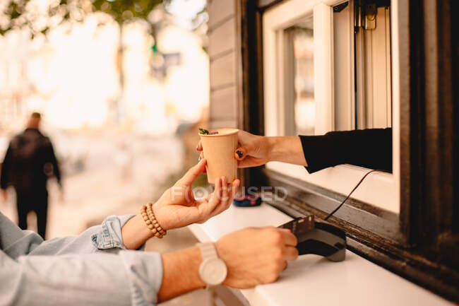 Cropped image of customer making payment with credit card buying coffee at cafe — Stock Photo