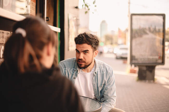 Пара разговаривает, сидя в кафе на тротуаре — стоковое фото
