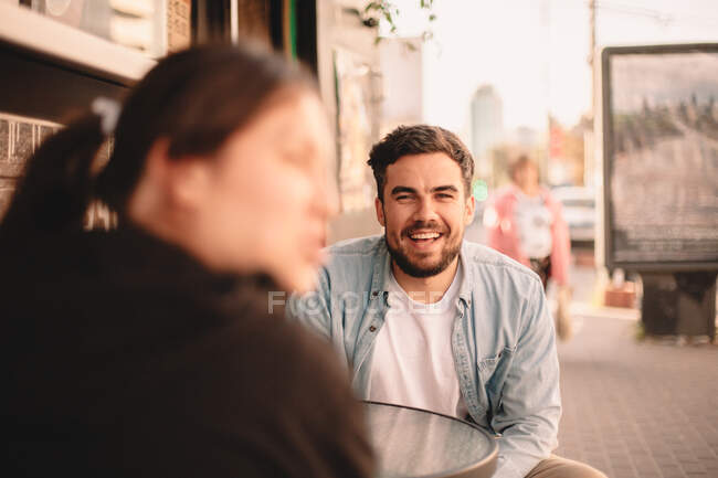 Homem feliz sentado com sua namorada no café da calçada — Fotografia de Stock