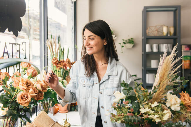 Beautiful young florist taking care of flower pots in her store — Stock Photo