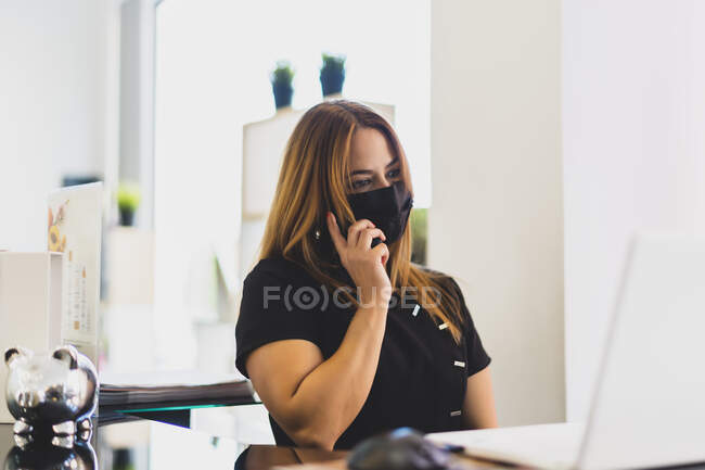 Mujer emprendedora contestando el teléfono de su negocio - foto de stock