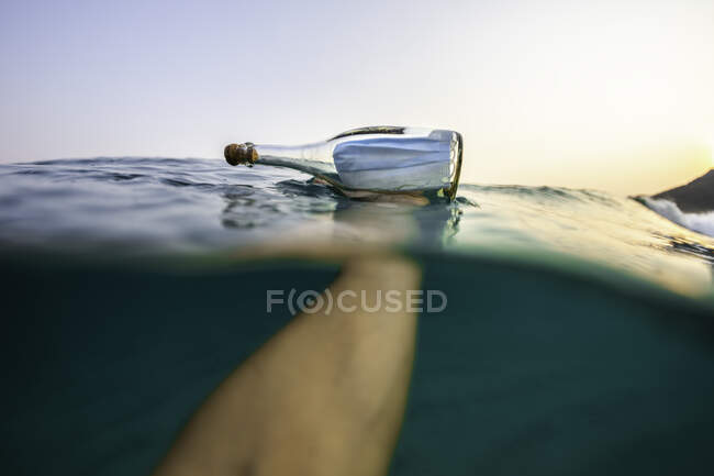 Primer plano de un vaso de agua con una boya y una botella en la costa del mar - foto de stock