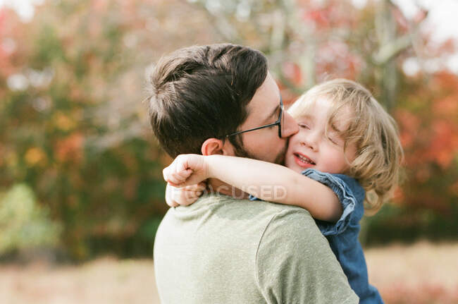 A happy toddler girl holding on to her father's neck — Stock Photo