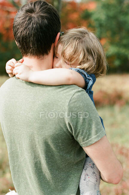 Молодой отец носит свою дочку, чтобы утешить ее. — стоковое фото
