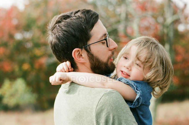 Щаслива дівчинка-малюк тримається за шию свого батька — стокове фото