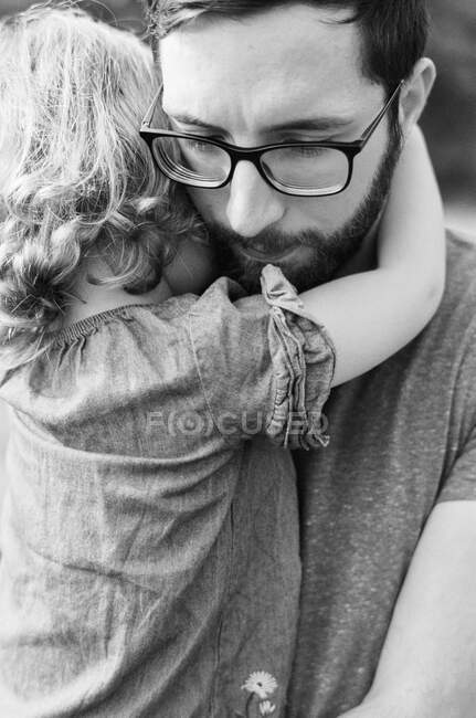 Bianco e nero primo piano di un padre millenario confortante figlia — Foto stock